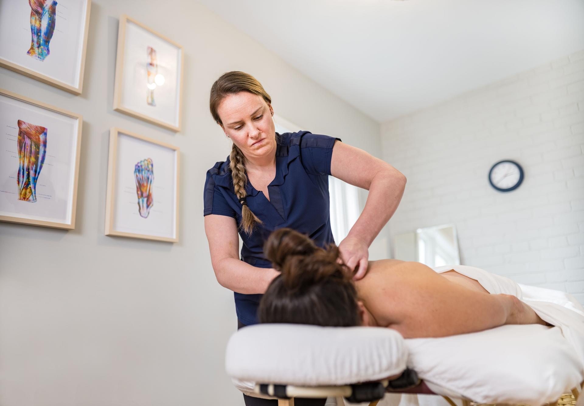 Female massage therapist treating female patient